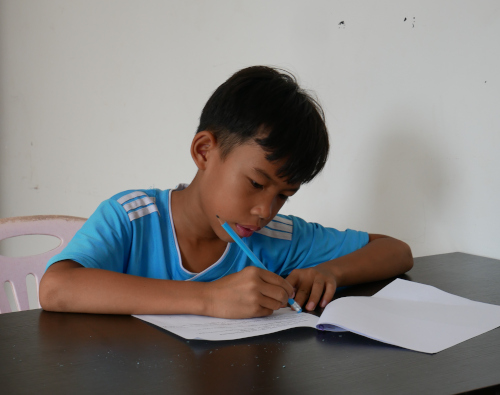 un enfant cambodgien écrit sur une feuille