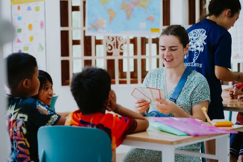 Une bénévole fait travailler des enfants avec des cartes illustrées en classe