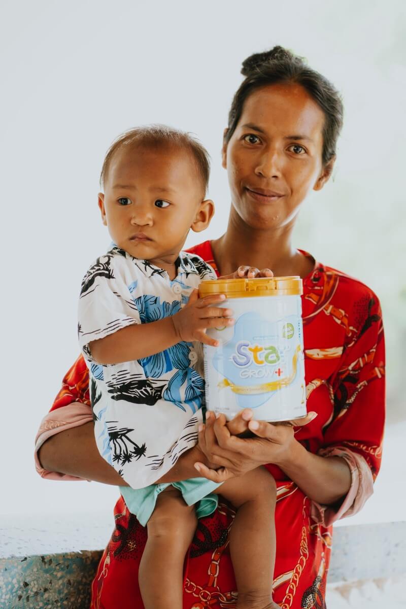 A mother and her child holding a tin of milk