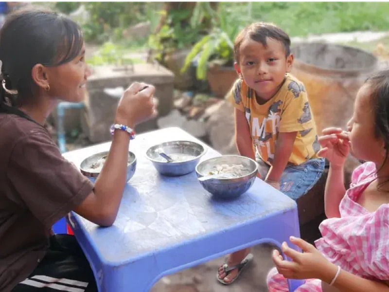 Des enfants cambodgiens qui mangent autour d'une table